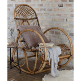 Vintage stílusú, növényi rattanból készült hintaszék enteriőrben párnával és pléddel borítva